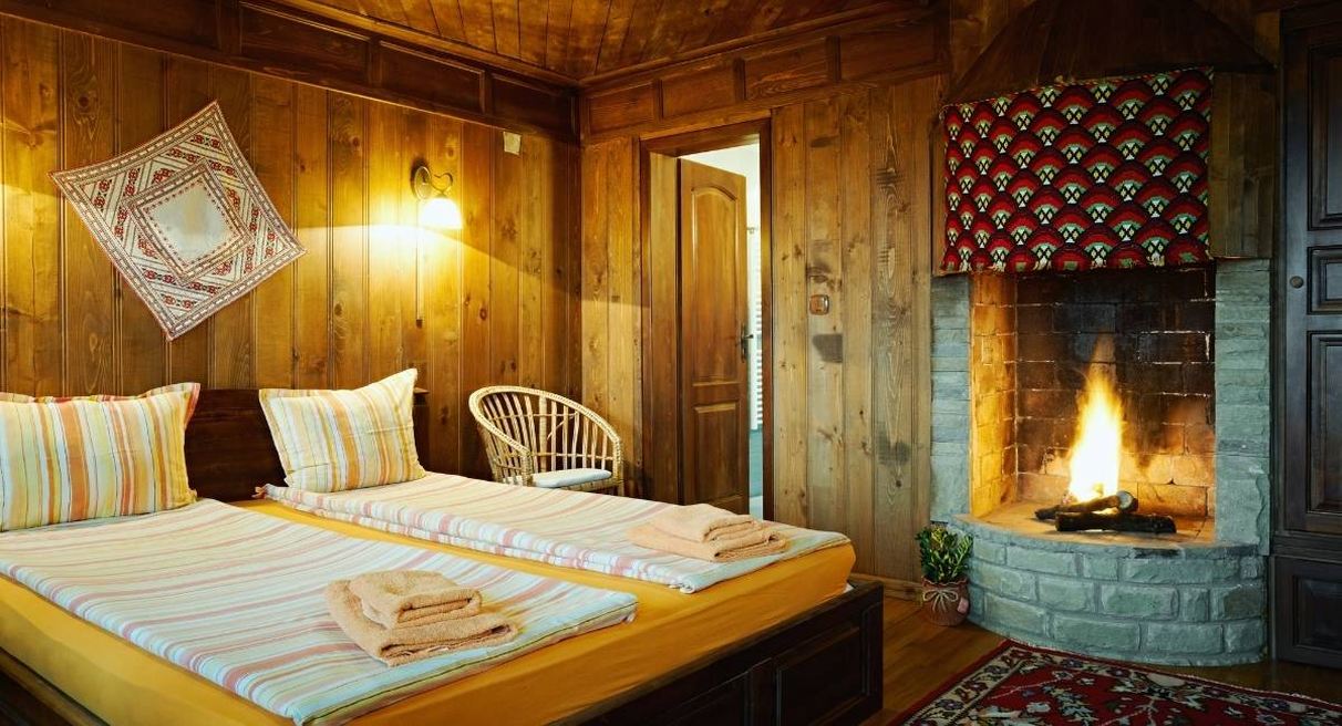 Chambre d hotes lambrissee de bois avec un lit double et une cheminee allumee