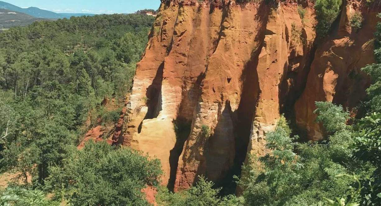 Falaises d'ocre rouge et orangé entourées de pins dans le Vaucluse
