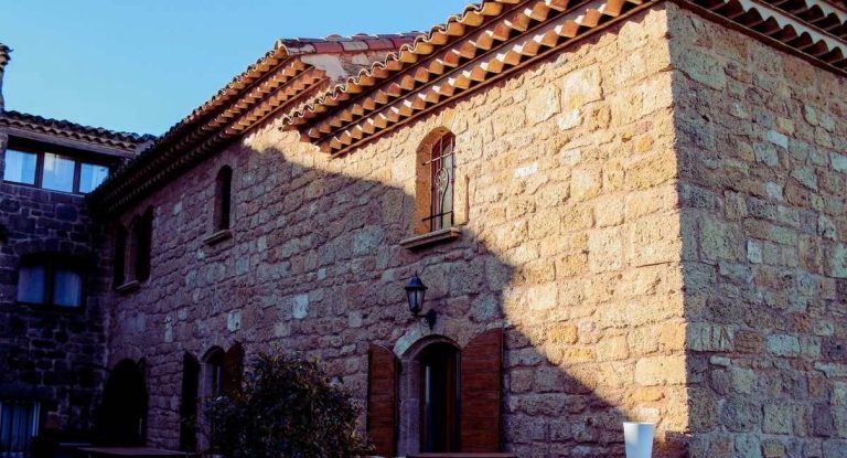 Façade d'une maison en pierre aux tuiles rondes et volets en bois en Provence