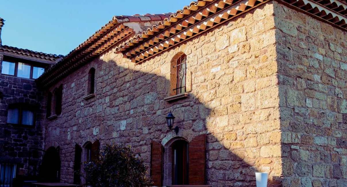 Façade d'une maison en pierre aux tuiles rondes et volets en bois en Provence
