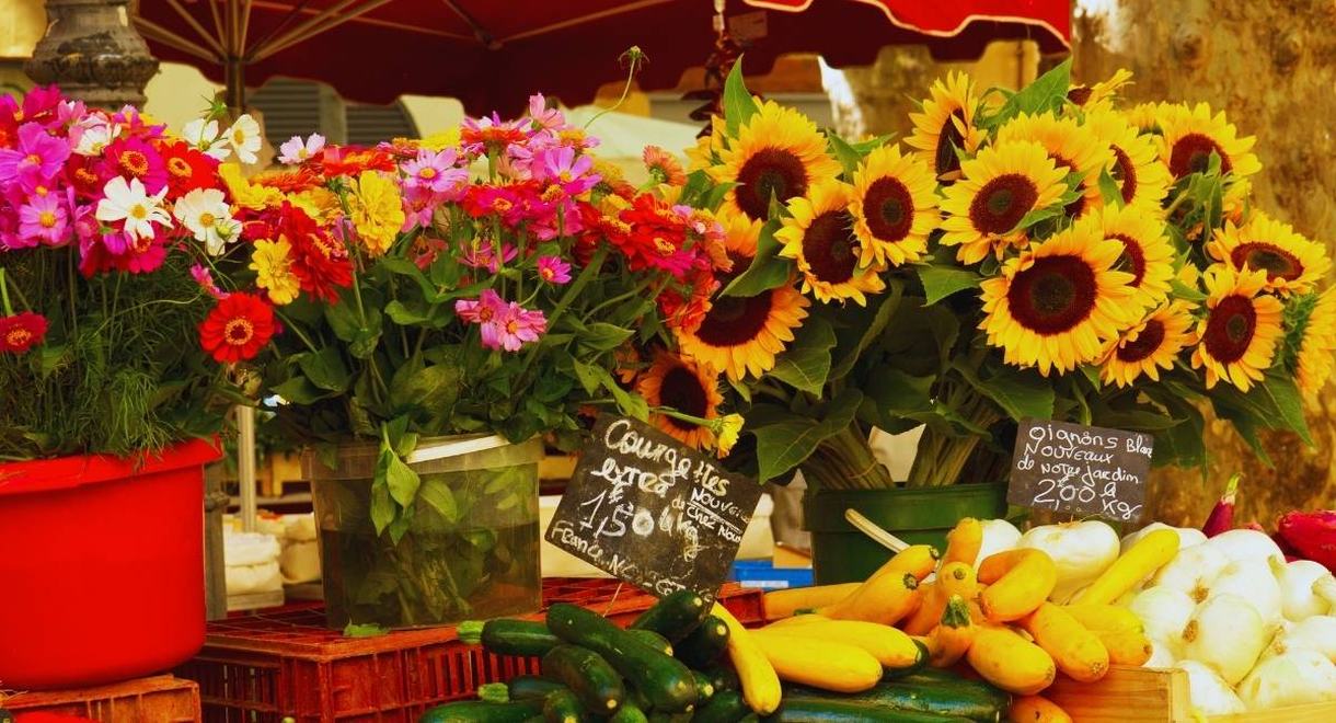 Étal de marché provençal avec tournesols, bouquets de fleurs et courgettes