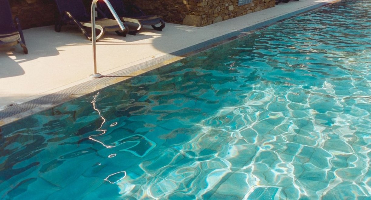 Piscine extérieure bordée de transats et d'un mur en pierre sèche au soleil