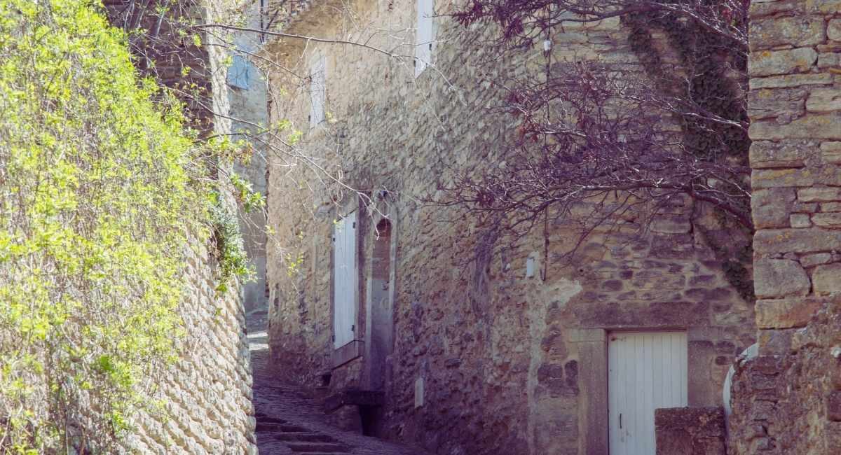 Ruelle pavee en pente bordee de maisons en pierre seche et de volets blancs