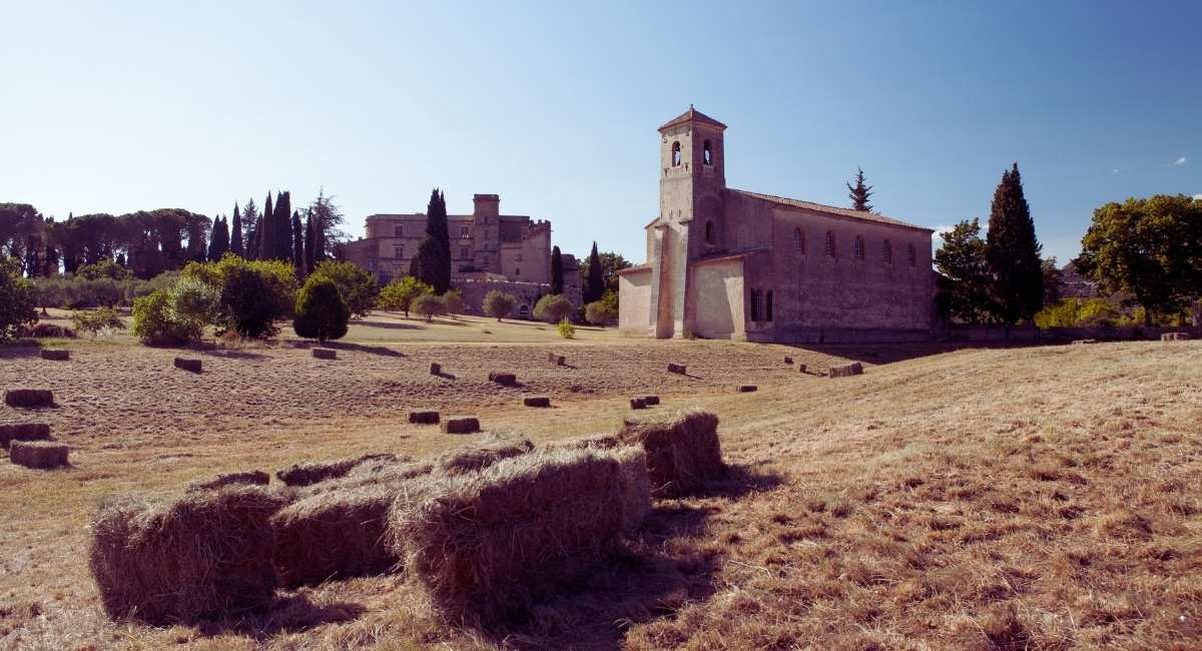 Château et temple en pierre au milieu d'un champ de foin dans le Luberon