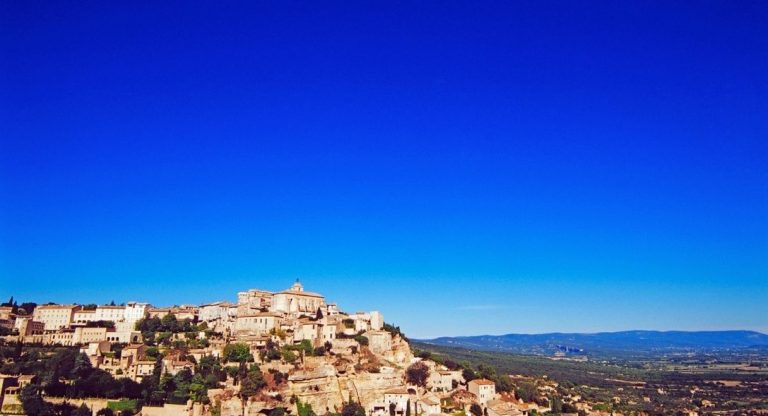 Village perché en pierre dominant la vallée du Luberon sous un ciel bleu