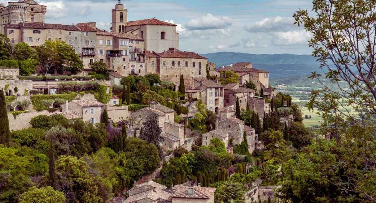 Village perche en pierre de Provence surplombant une vallee boisee
